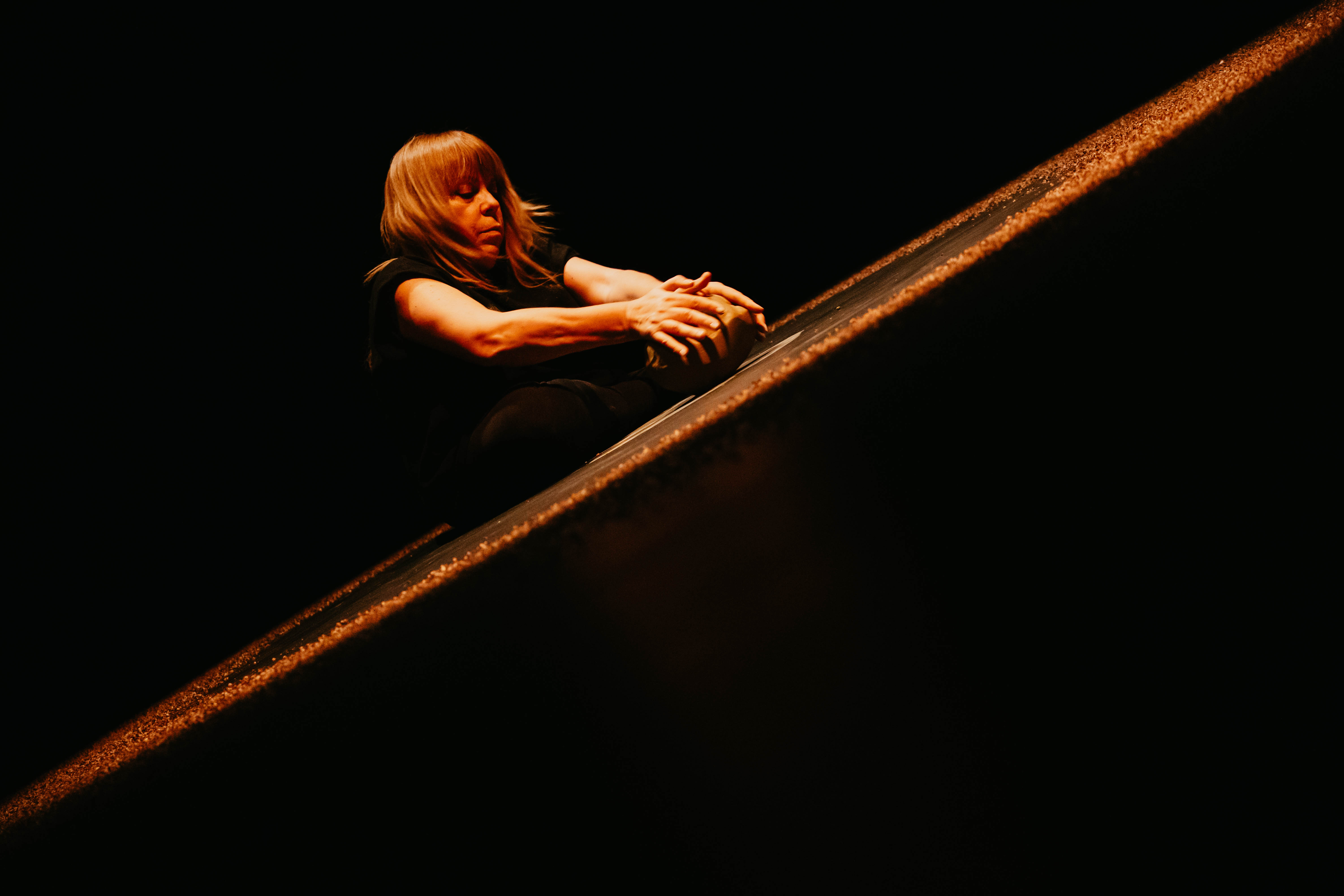 Vivi sitted haw her arms extended forward rolling a piece of clay