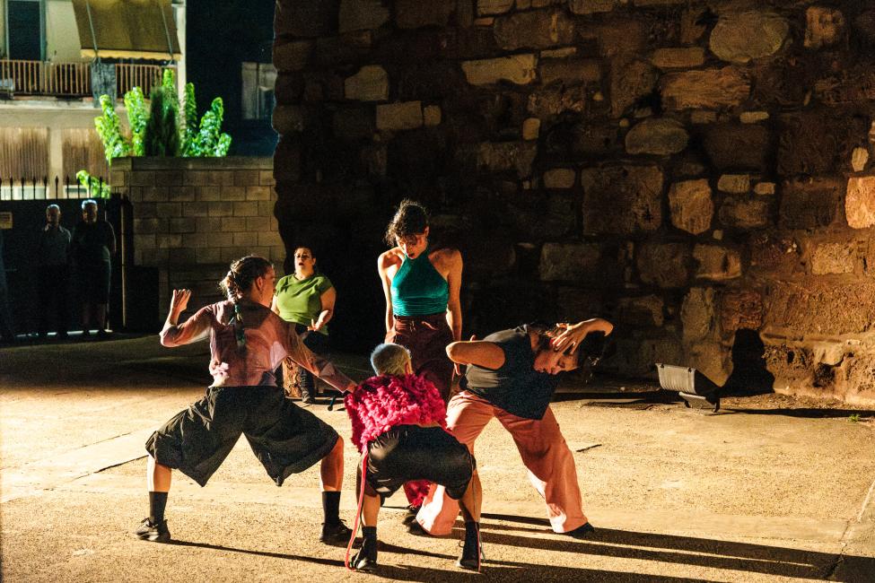 Τέσσερις γυναίκες σχηματίζουν έναν πυρήνα σε μια διαγώνιο την οποία οδηγεί καθιστή μια πέμπτη γυναίκα που φαίνεται στο βάθος